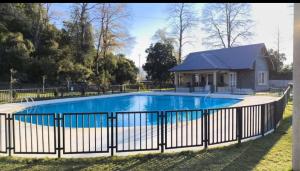 a swimming pool with a fence and a house at Pucon, casa condominio in Pucón