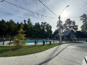 a house with a fence and a tree in a yard at Pucon, casa condominio in Pucón