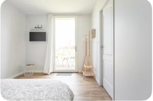 a white bedroom with a bed and a window at L’Orée des Vignes in Saint-Sulpice-de-Faleyrens