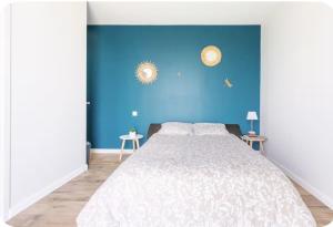 a bedroom with a large bed with a blue wall at L’Orée des Vignes in Saint-Sulpice-de-Faleyrens