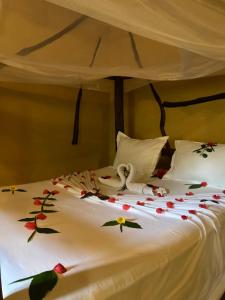 a bed with flowers on it with two swans on it at KC Bungalows in Nungwi +5 photos