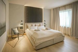 a white bedroom with a large bed and a chair at Boutique Hotel an der Mosel - ehemalig Hotel Kreuter in Koblenz