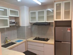 a kitchen with white cabinets and a sink and a refrigerator at UrbaNest in Kota Bharu