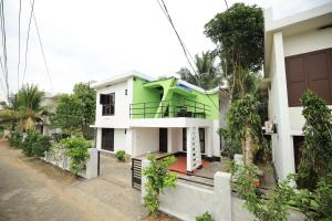 a green and white house with trees in front of it at Ashiyana Homes in Nedumbassery