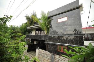 a house with a black facade with a palm tree at Ashiyana Homes in Nedumbassery