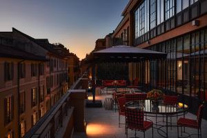 a patio with tables and chairs and an umbrella at Rocco Forte The Carlton in Milan