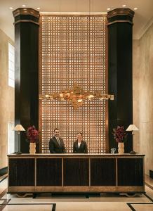 two people standing at a reception desk in a lobby at Rocco Forte The Carlton in Milan