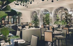 a restaurant with tables and chairs and plants at Rocco Forte The Carlton in Milan
