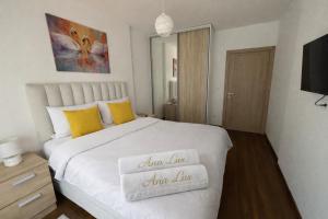 a bedroom with a large white bed with yellow pillows at Ana Lux Master apartament in Podgorica