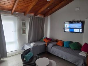 a living room with two beds and a tv at CORDOBA AEROPUERTO KEMPES QUORUM HOSPITAL ALLENDE PRIVADO Siglo XXI Universidad PASCAL Templo Mormon de Villa Belgrano in Córdoba