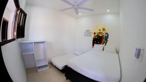 a white room with a bed and a ceiling fan at Hostal Barrio Abajo in Barranquilla