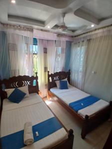 two beds in a room with blue and white at Kariba 8 in Mombasa +10 photos