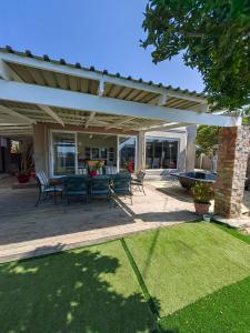 a patio with a table and chairs under a pergola at Karibu Self-catering Accommodation in Hermanus