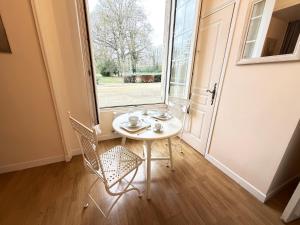 a table and chairs in a room with a window at Studio au cœur du château in Monchy-Humières +8 photos