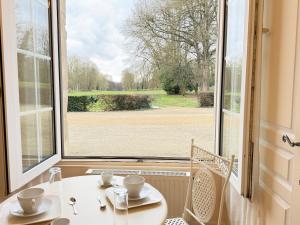 a table and chairs in front of a large window at Studio au cœur du château in Monchy-Humières