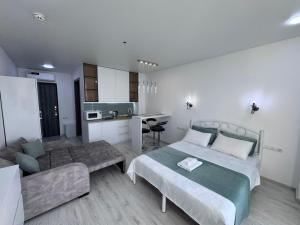 a bedroom with a bed and a couch and a kitchen at Batumi in the waves in Batumi