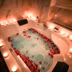 a bath tub filled with red roses in a bathroom at Glamour & jacuzzi privé Chambéry in Chambéry +15 photos