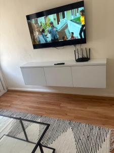 a white entertainment center with a flat screen tv on a wall at Bello Departamento Completo con 2 recámaras! in San Baltasar