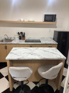 a kitchen with a counter with two chairs and a sink at Bello Departamento Completo con 2 recámaras! in San Baltasar