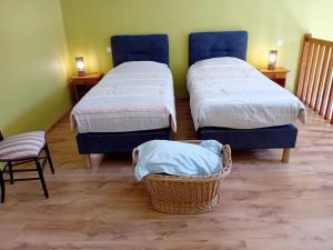 two beds in a room with two chairs and a basket at Ferme du Pigeonnier in Montceau-et-Écharnant