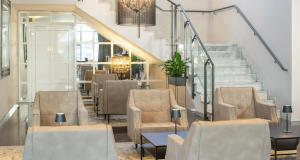 a lobby with chairs and a staircase with a table at Victor's Residenz-Hotel Saarlouis in Saarlouis +42 photos