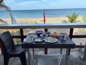 a tray of food on a table on a balcony with the beach at Hollywood Beachfront Bed & Breakfast in Mamburao