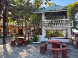 a group of picnic tables in front of a building at Hollywood Beachfront Bed & Breakfast in Mamburao