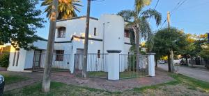 a white house with a gate in front of a street at Casona El Rosedal in Bell Ville