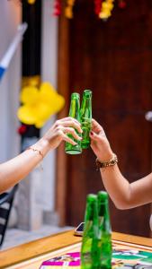 two people are holding up green glasses at Hostal Barrio Abajo in Barranquilla