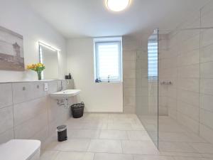 a white bathroom with a shower and a sink at Ferienwohnung NorderHafen in Norden +32 photos