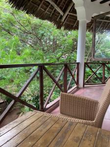 a wicker chair sitting on top of a wooden deck at KC Bungalows in Nungwi