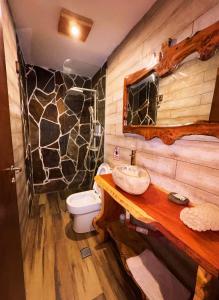 a bathroom with a toilet and a stone wall at Casa Nuna in Tilcara