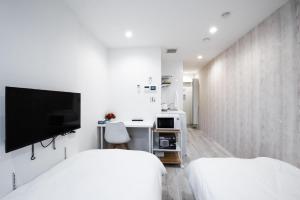 a white bedroom with two beds and a tv at Boa Sorte Hotel AD0515 in Tokyo