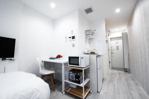 a white room with a bed and a desk with a microwave at Boa Sorte Hotel AD0515 in Tokyo