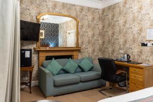 a room with a couch and a desk and a mirror at Grampian Hotel in Perth