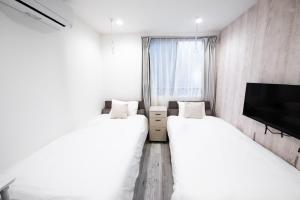 two white beds in a room with a tv at Boa Sorte Hotel AD0515 in Tokyo