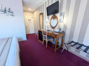 a hotel room with a desk and a mirror at Hotel des Abers in Saint Malo