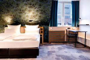 a hotel room with two beds and a desk at Motel One Frankfurt-Hauptbahnhof in Frankfurt