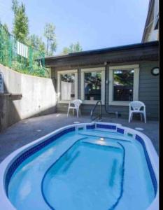 a swimming pool with two chairs and a house at 2 Bed 2 Bath with Fire Place in Fernie