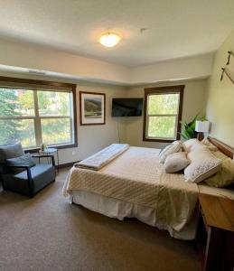 a bedroom with a bed and a chair and windows at 2 Bed 2 Bath with Fire Place in Fernie +30 photos