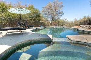 a swimming pool with a chair and an umbrella at Blue Stone Chateau Yosemite Pool Spa Secluded in Abbeyville