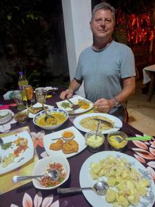 a man sitting at a table with plates of food at Chapel Home Stay in Ahungalla