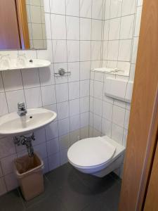 a white bathroom with a toilet and a sink at Gasthaus Decker in Mittenaar