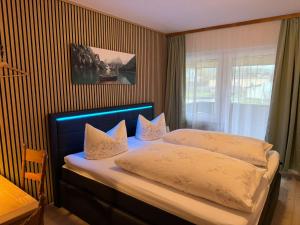 a bedroom with a bed with two pillows and a window at Gasthaus Decker in Mittenaar +2 photos