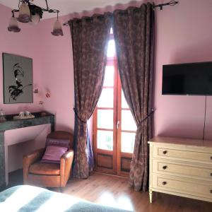a bedroom with a window and a chair and a television at Chambres d'Hôtes Le Loubet in LʼIsle-Jourdain