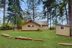 a small house in a yard with logs on the grass at Eagle Beach Retreat in Freeland