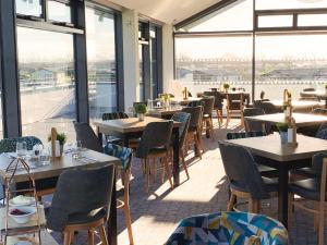 a restaurant with tables and chairs and large windows at Unity Beach in Berrow