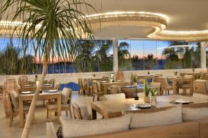 a restaurant with tables and chairs and a palm tree at Anax Resort and Spa in Agios Ioannis Mykonos