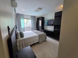 a bedroom with a bed and a flat screen tv at Inocoop house in Camaçari +11 photos