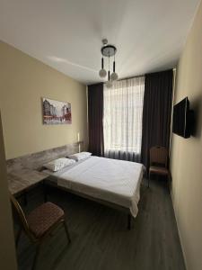 a bedroom with a bed and two chairs and a window at Assorti in Semey